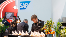 zwei Männer bereiten Essen zu hinter einer BAr
