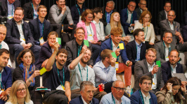 Menschen im Publikum heben bunte Karten hoch