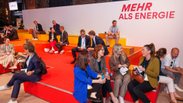 Menschen auf einem Sitzpodest in den Farben des BDEW Kongress 2025