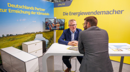 Menschen unterhalten sich an einem Ausstellungsstand