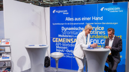 Menschen unterhalten sich an einem Ausstellungsstand
