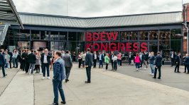 Menschen unterhalten sich vor einer Glasfassade mit der Aufschrift 'BDEW Kongress 2022'
